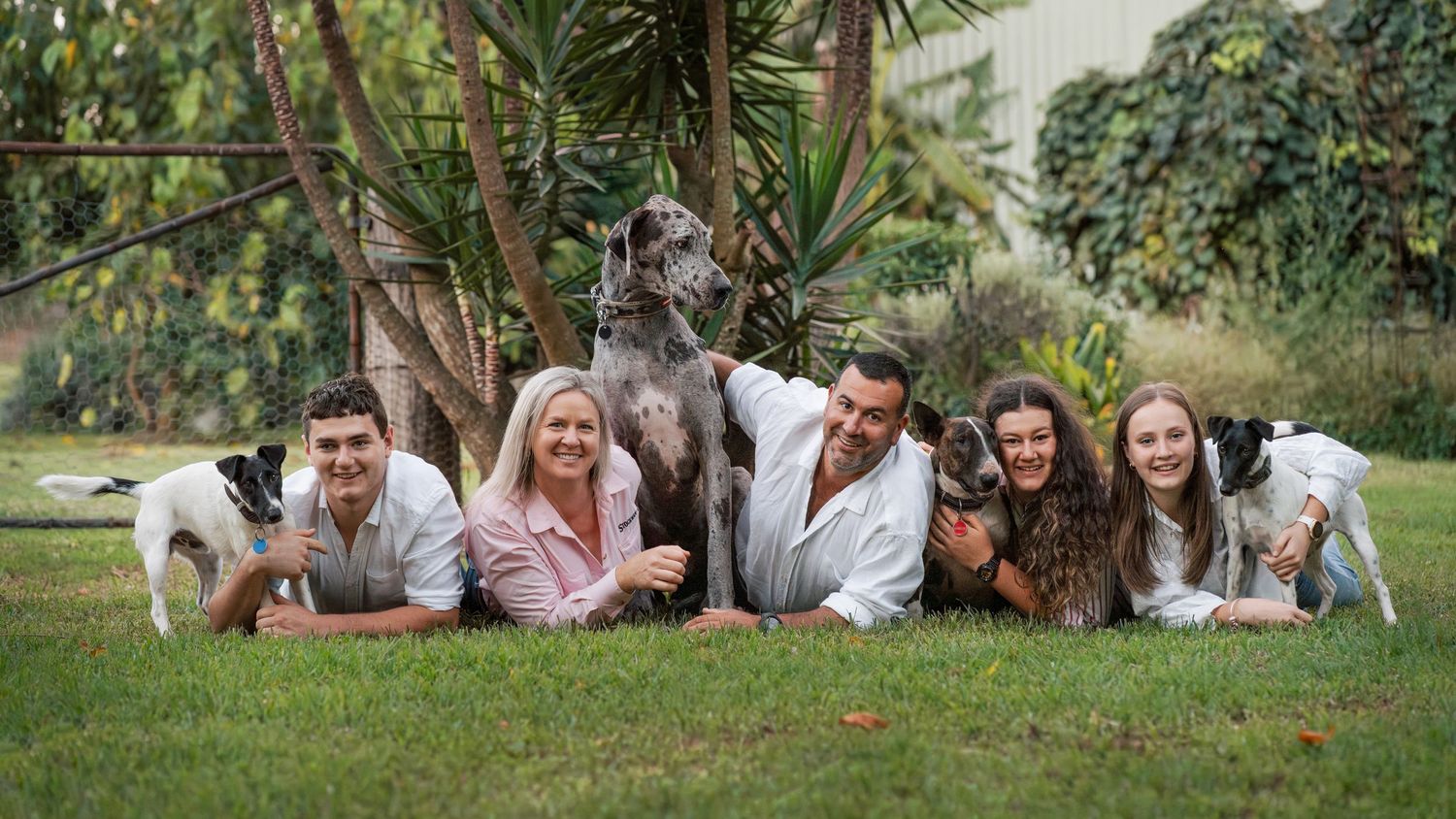 family of five and their four dogs laying on the grass during their family photoshoot in Central Coast's Mangrove mountian