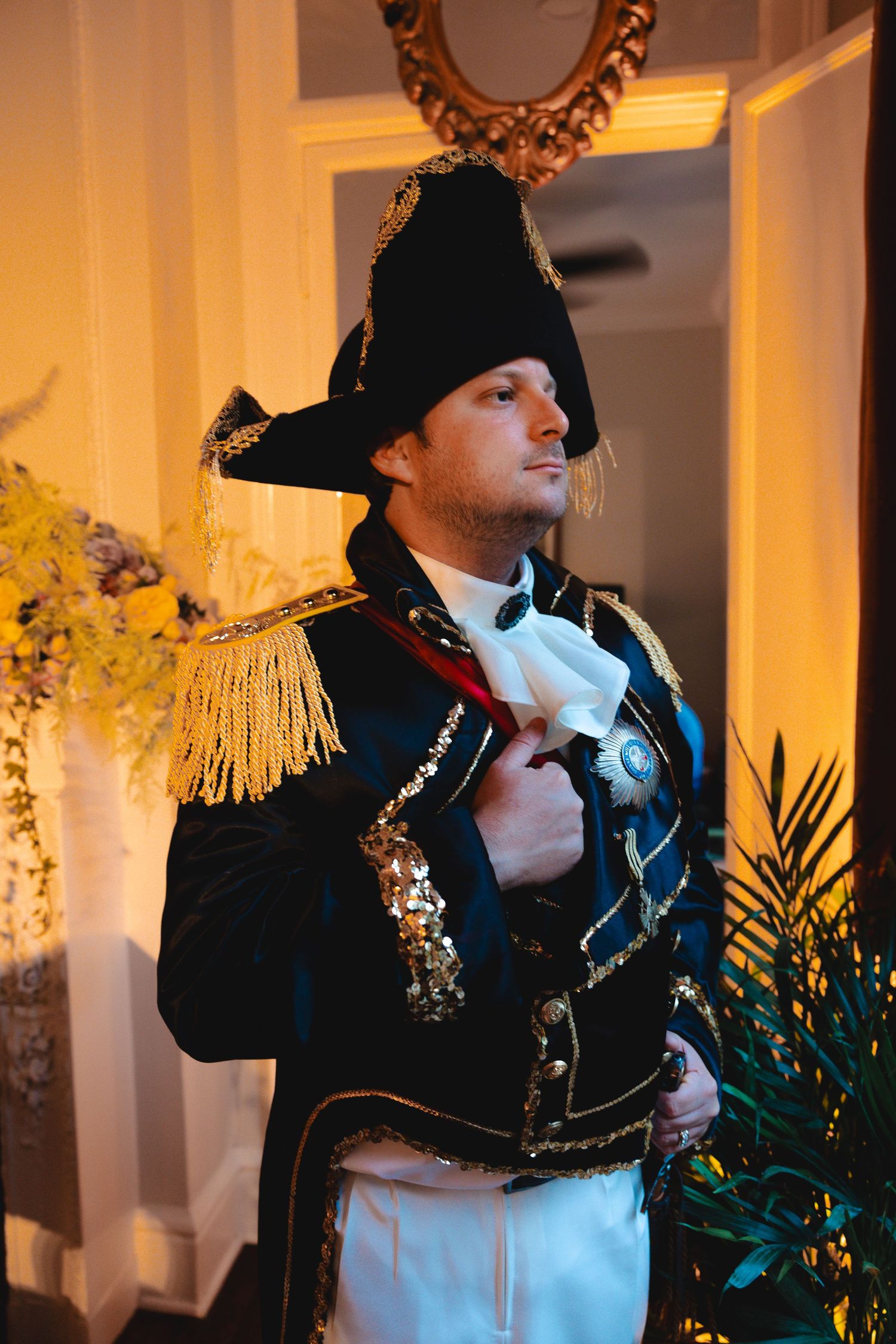 Man in Napoleonic military costume with epaulettes and bicorne hat at formal event.