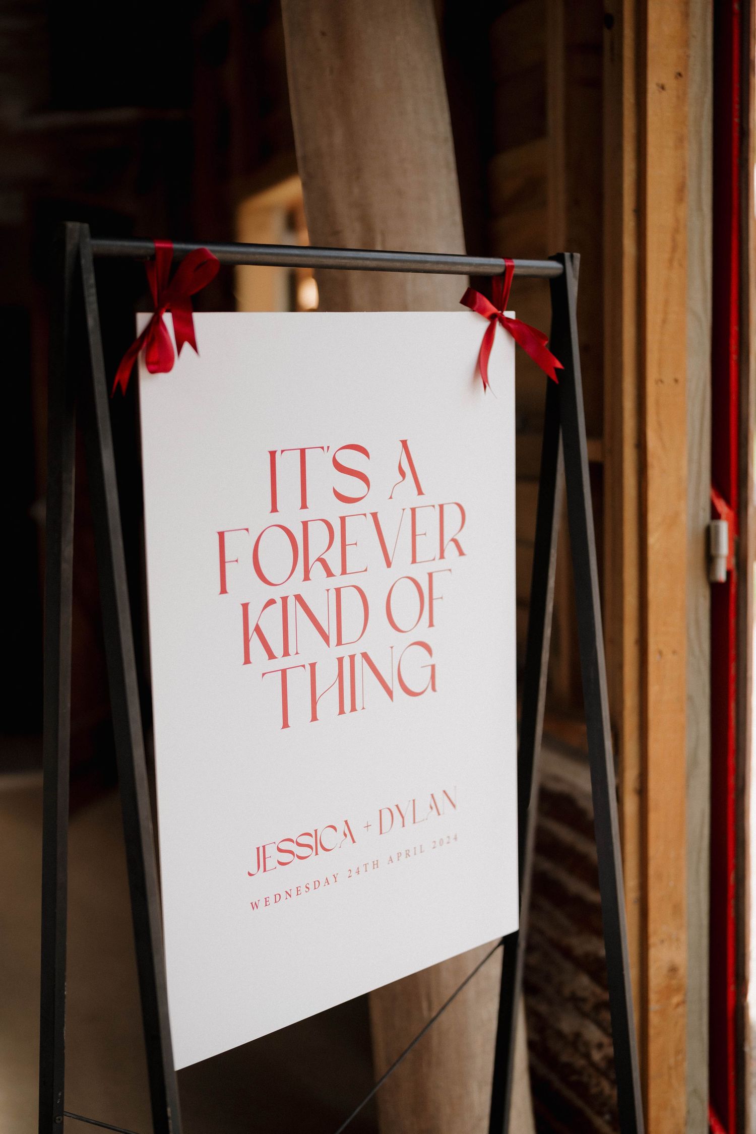 White wedding welcome sign with red text reading It's A Forever Kind Of Thing for Jessica and Dylan.