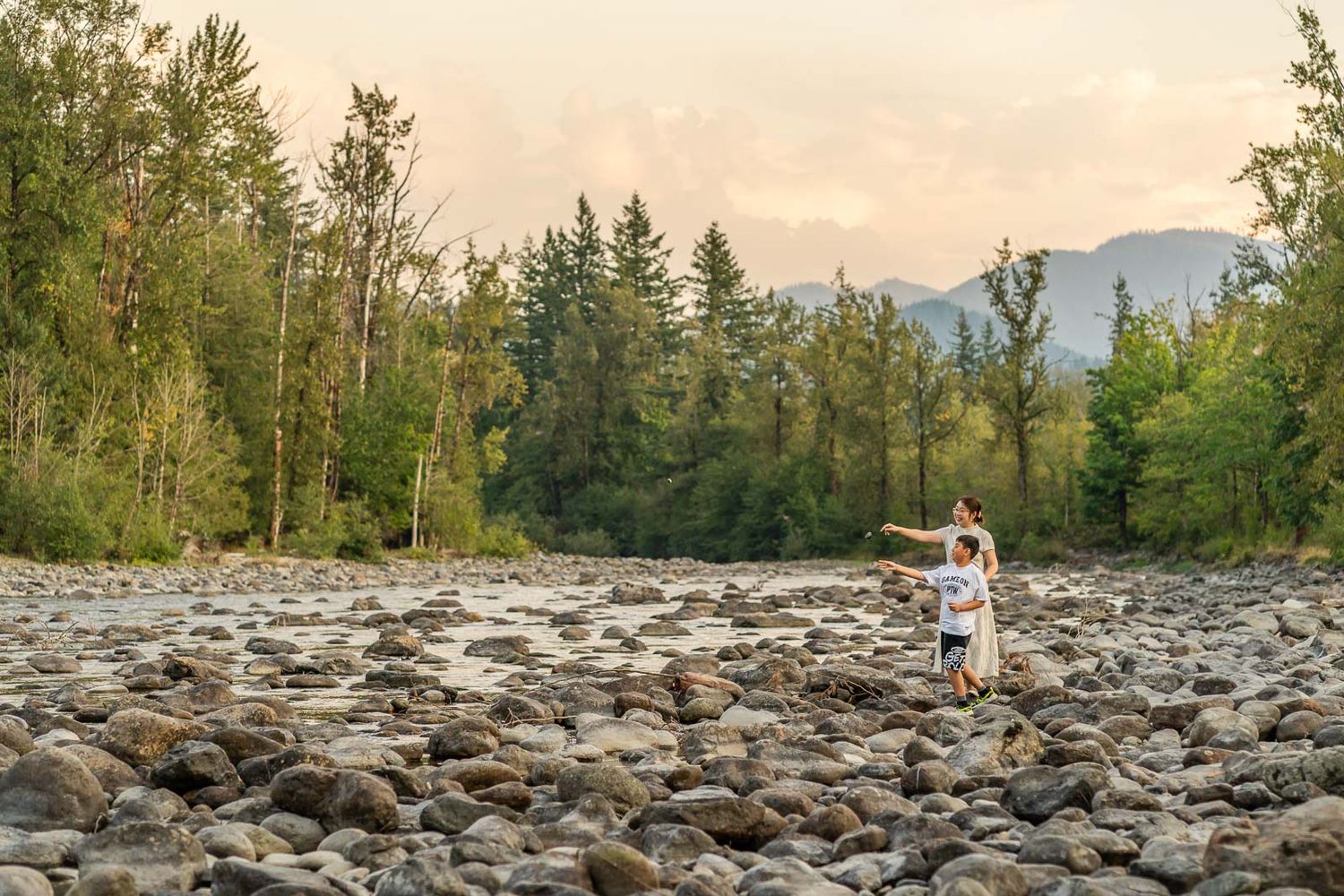Mother and son throw rocks in North Bend by the river.