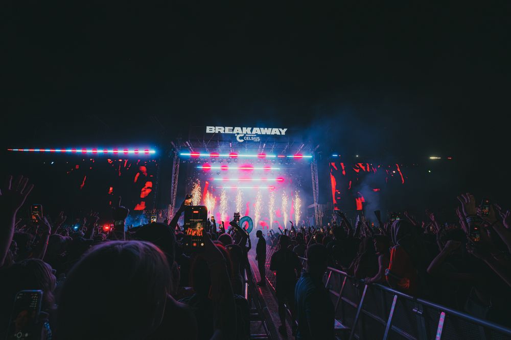Crowd at Break Away music festival enjoying a vibrant stage light show at night.