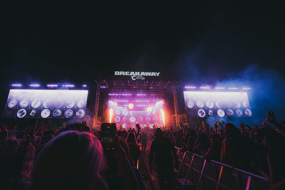 Breakaway Music Festival stage lit with colorful lights at night, crowd of fans gathered in front.