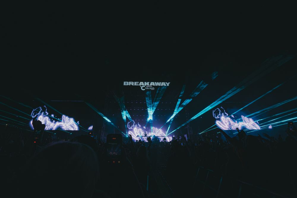 Breakaway Music Festival stage with laser light show and LED screens illuminating a dark concert crowd.