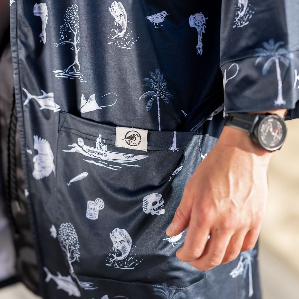 Navy blue patterned shorts with skull and tropical print, worn with a matching shirt and black watch.