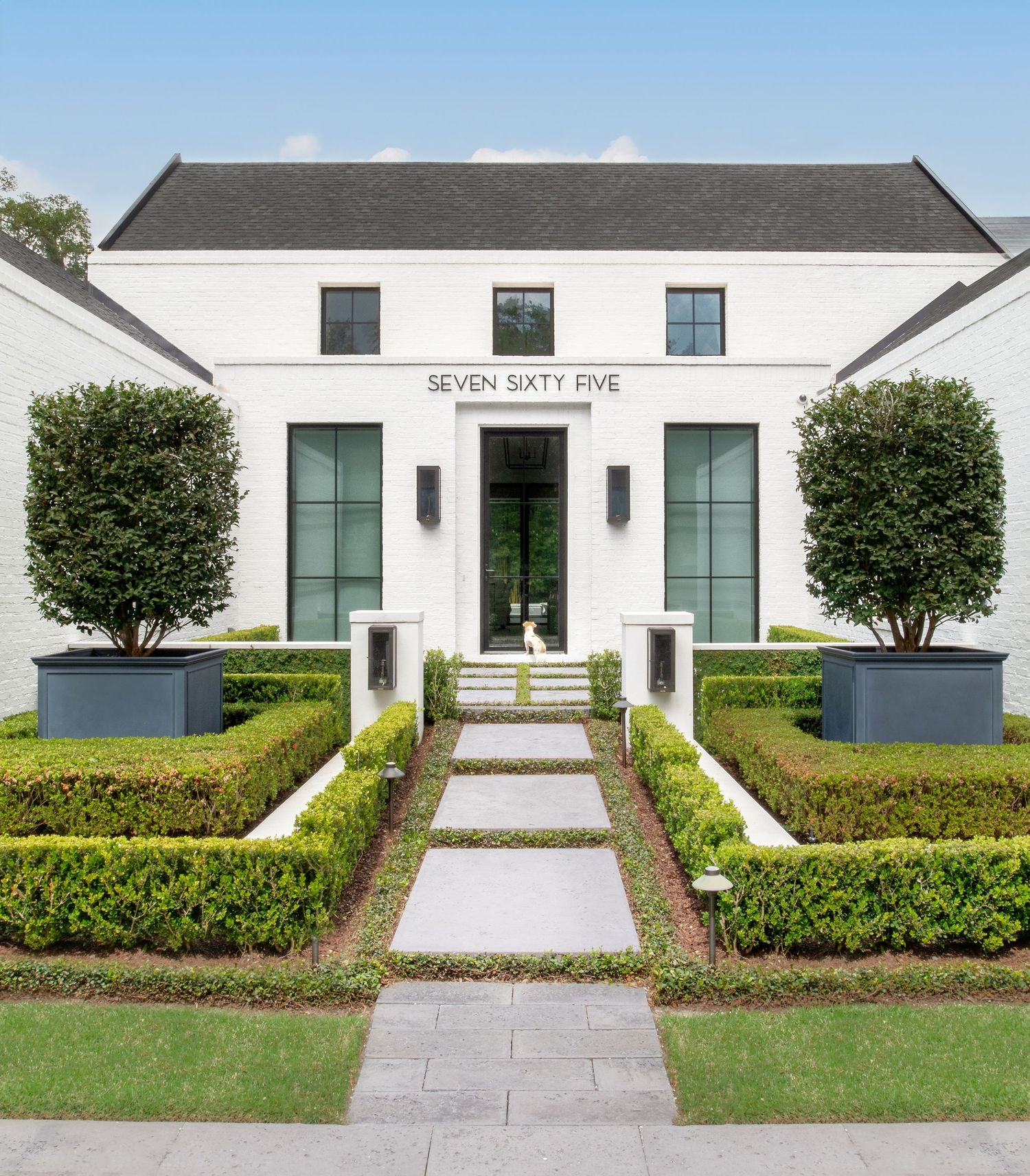 Elegant white modern home exterior with manicured hedges, topiaries, and stone pathway at Seven Sixty Five.
