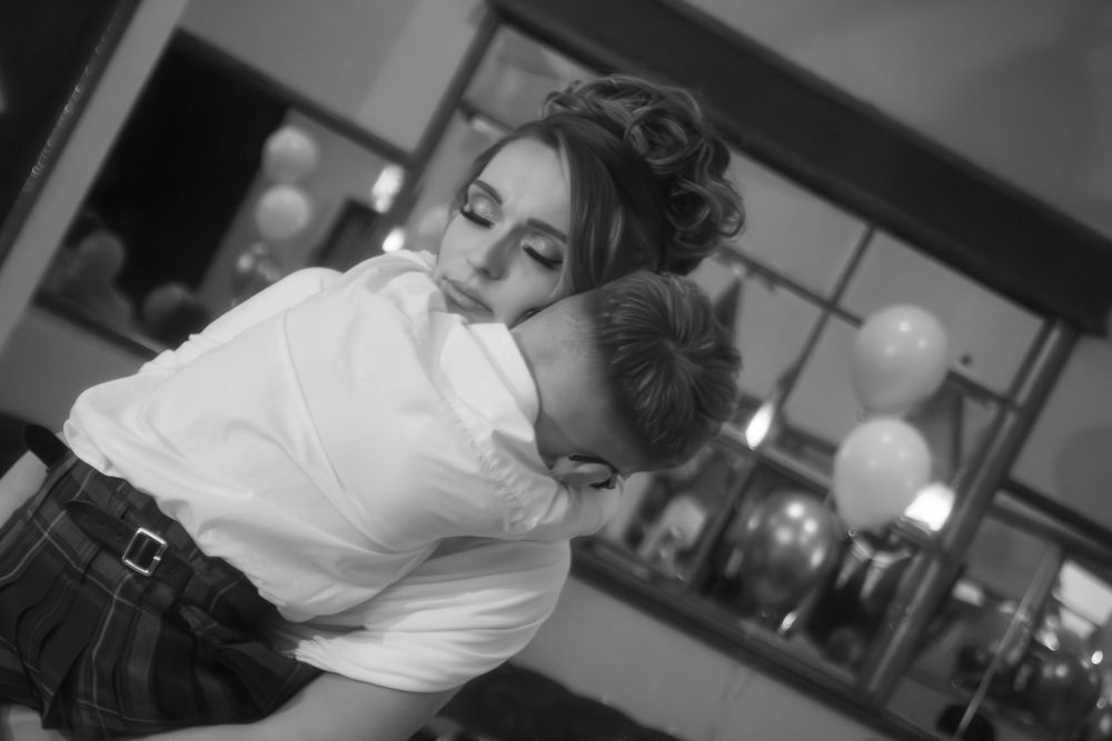 Black and white photo of a woman embracing a boy in a kilt at a First Holy Communion celebration.