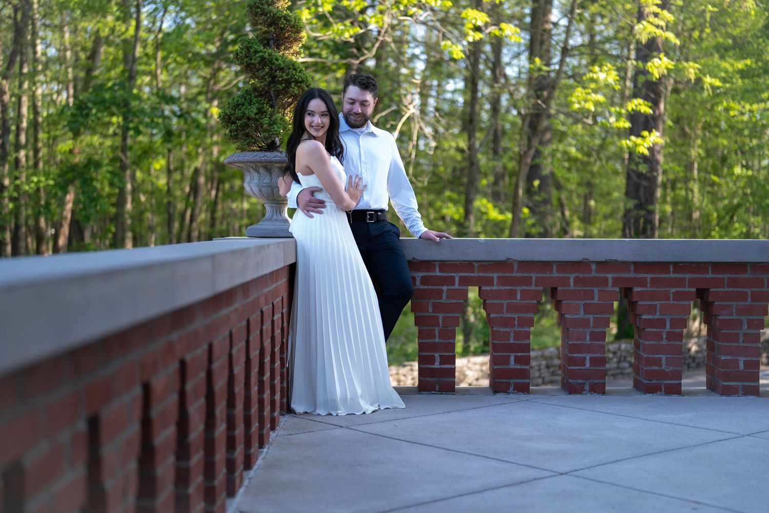 engaged couple pose on a brick bridge at Jeffrey Mansion