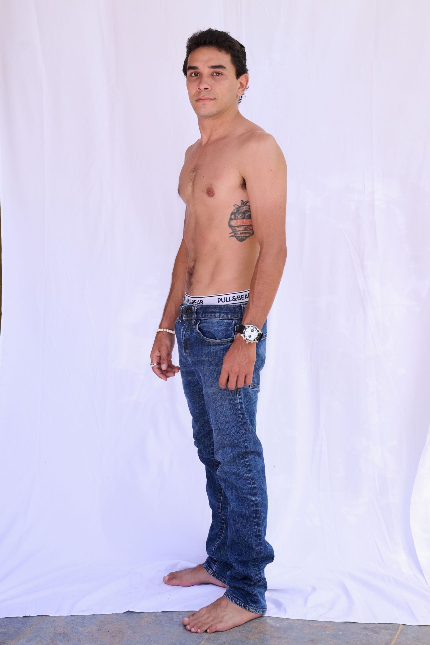 Model poses in white crop top and denim against light blue background in series of artistic fashion shots.