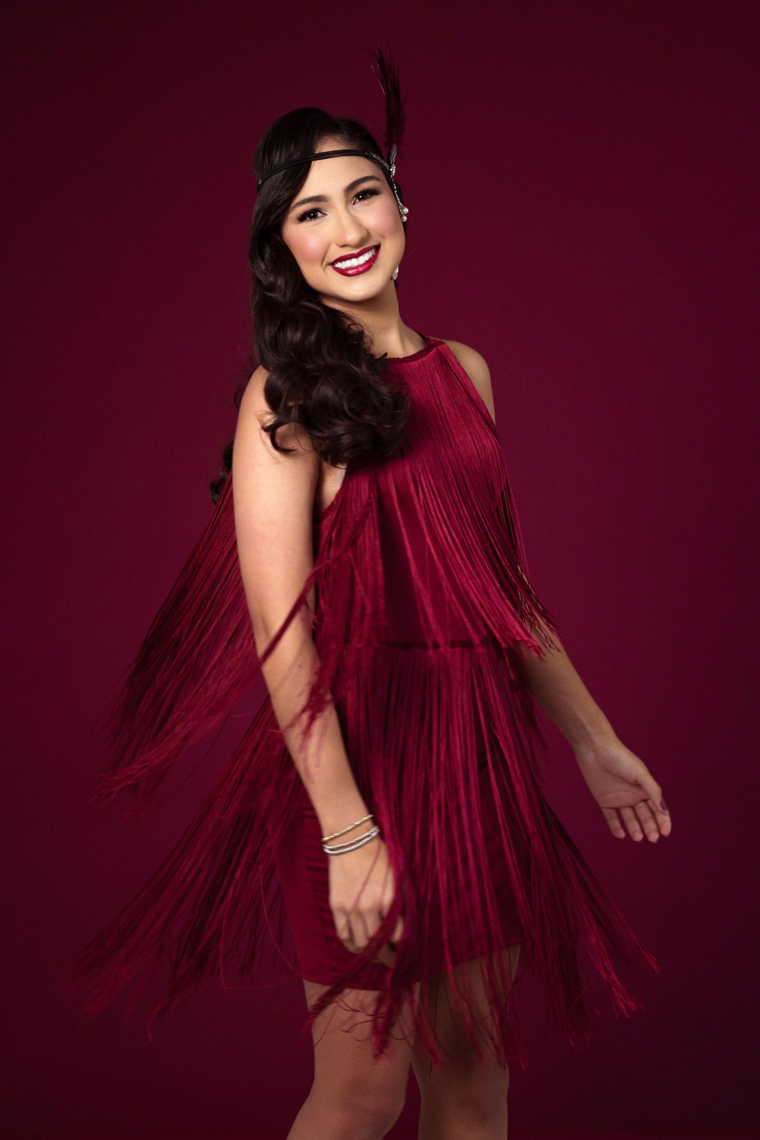 Vintage-inspired red fringe dress captured against deep burgundy background.