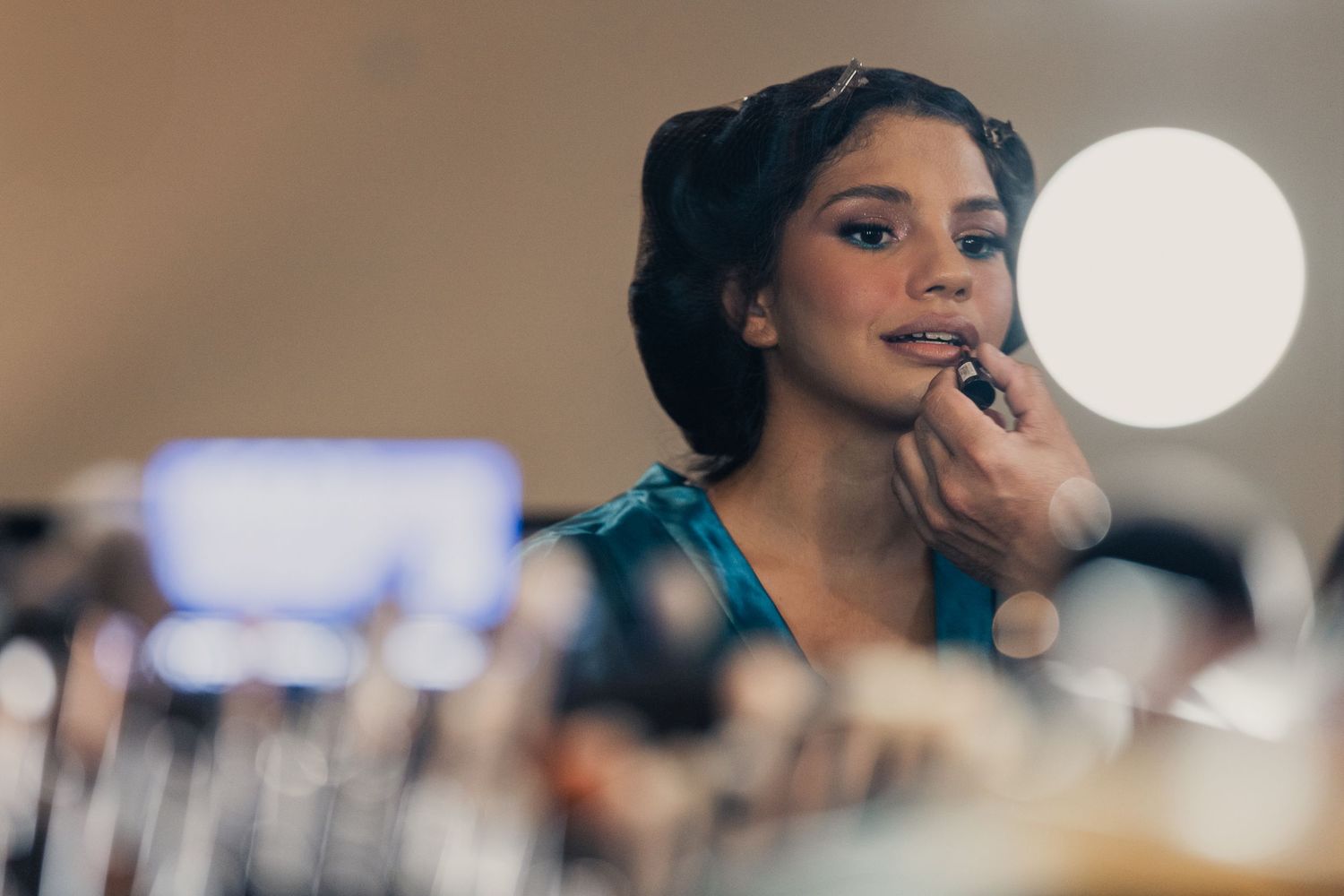 A person in formal attire smiles while looking away during an indoor event.