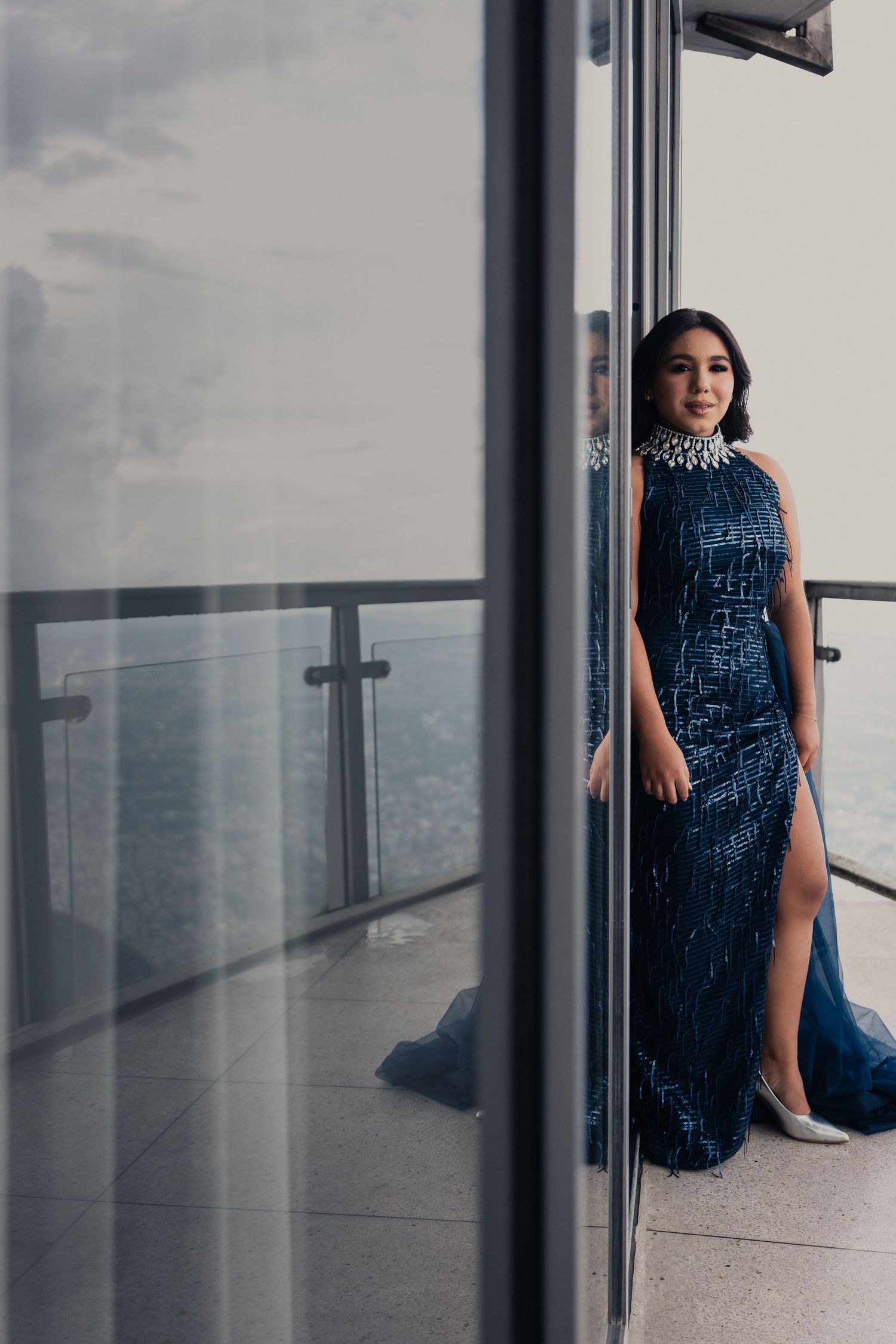 A series of photos showing a person in a sparkly blue evening gown posing in a modern hallway with glass walls.