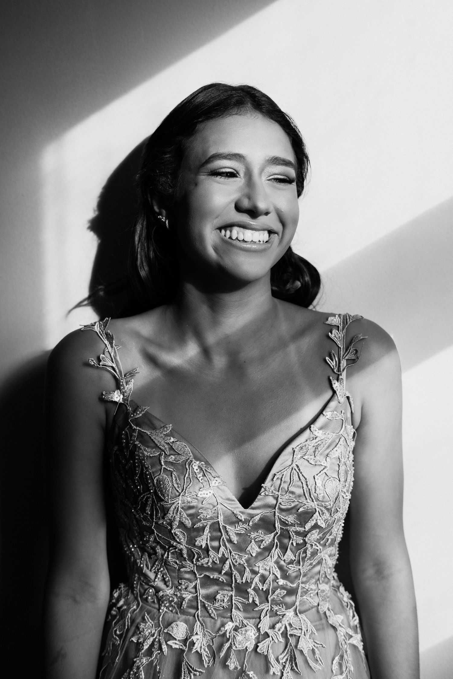 Black and white portrait series showing joyful expressions and a detailed lace dress with floral embellishments.