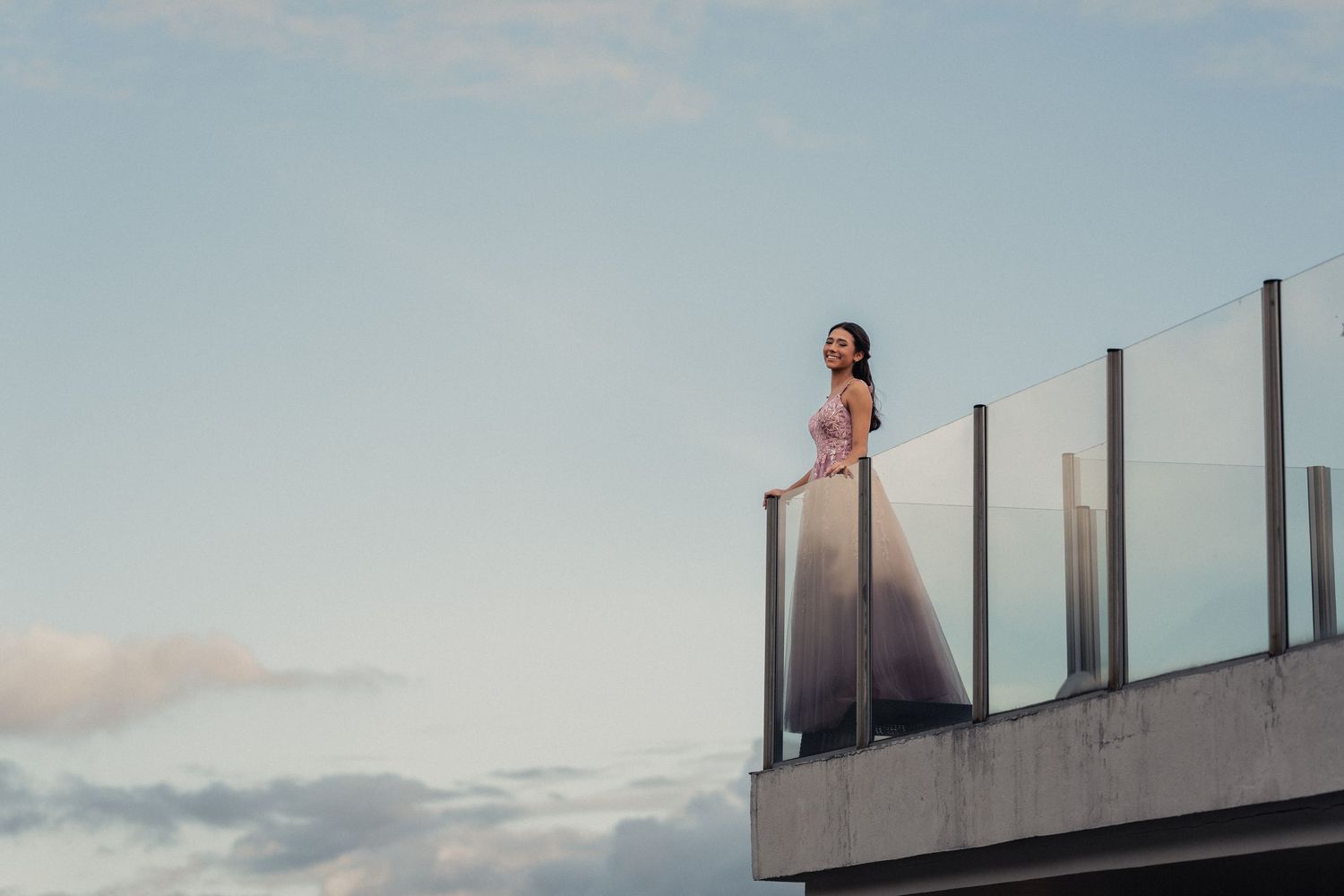 A dramatic silhouette of a person standing on a rooftop against a cloudy sky at sunset.