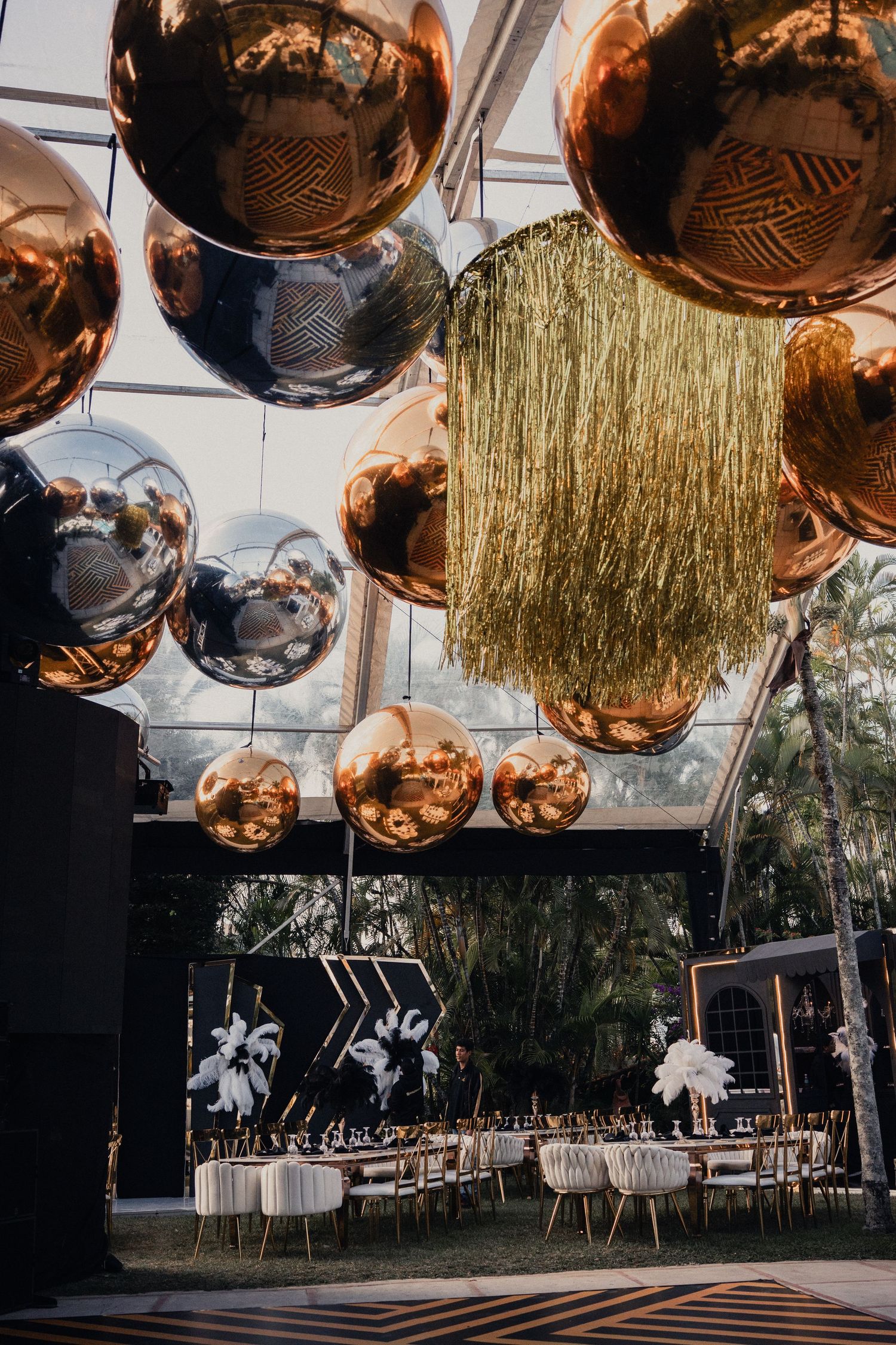 Elegant wedding reception venue decorated with copper disco balls and gold tinsel hanging from ceiling.