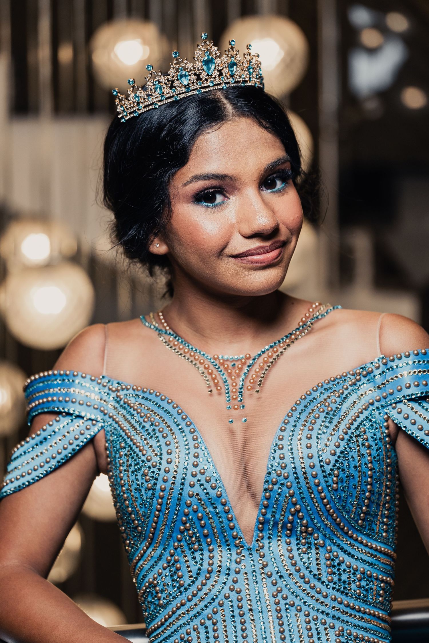 Ornate turquoise gown adorned with intricate beadwork and crystals photographed in a glamorous setting.