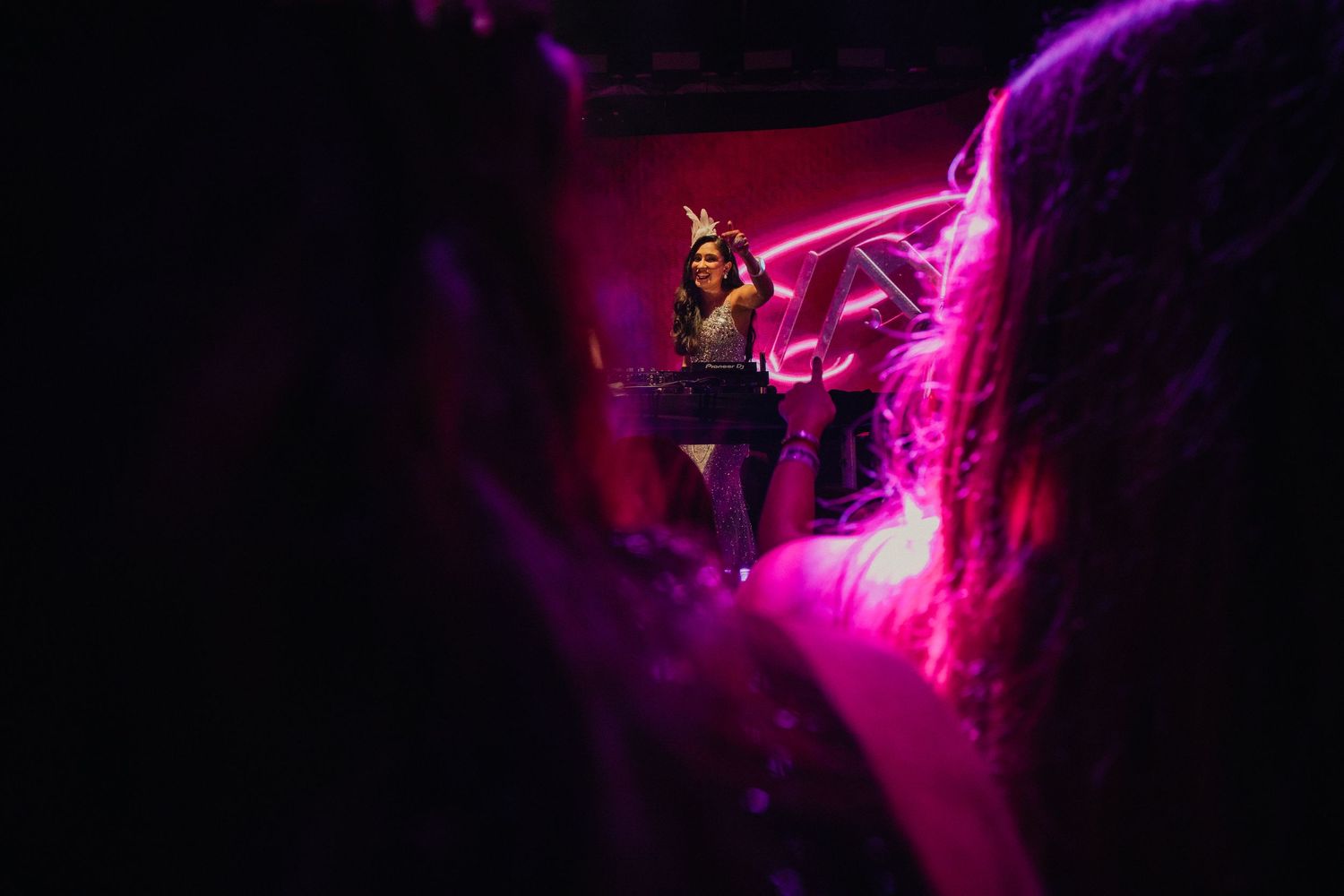 Vibrant pink and purple lighting creates an atmospheric glow at a nightclub event.