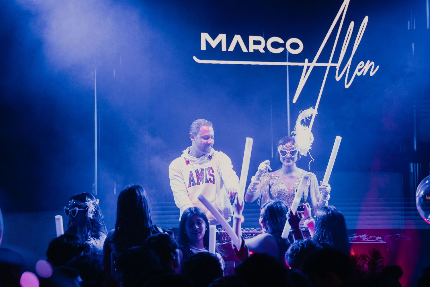 Concert stage illuminated with blue lights and digital displays showing text against dark background.