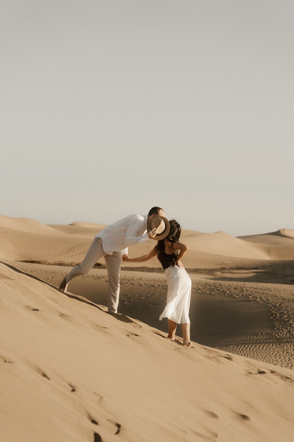 Destination wedding photographer capturing a sweet kiss against the setting sun in the desert.