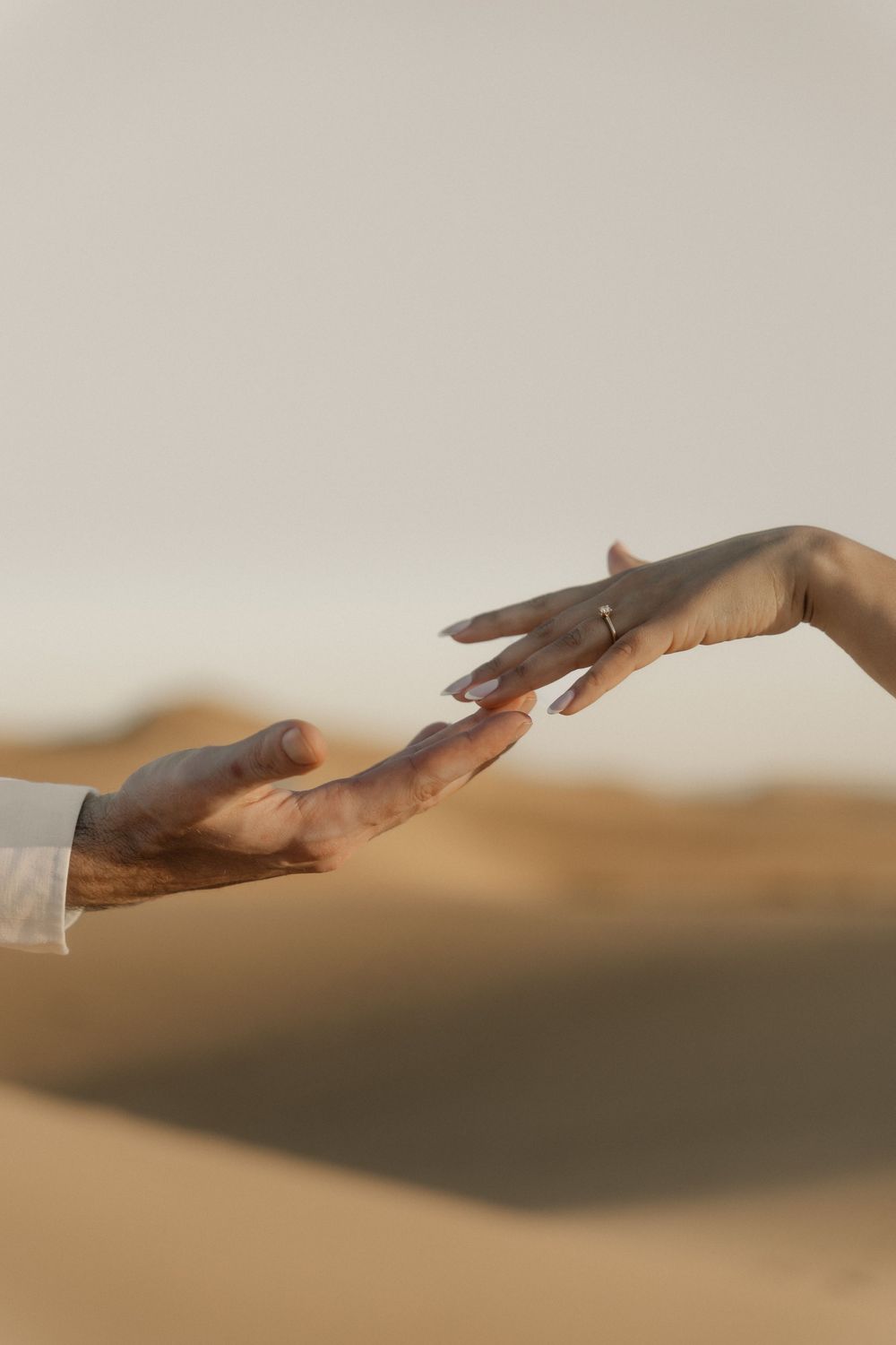 Epic wide shot of a romantic couple holding hands, surrounded by minimalist golden sand dunes.