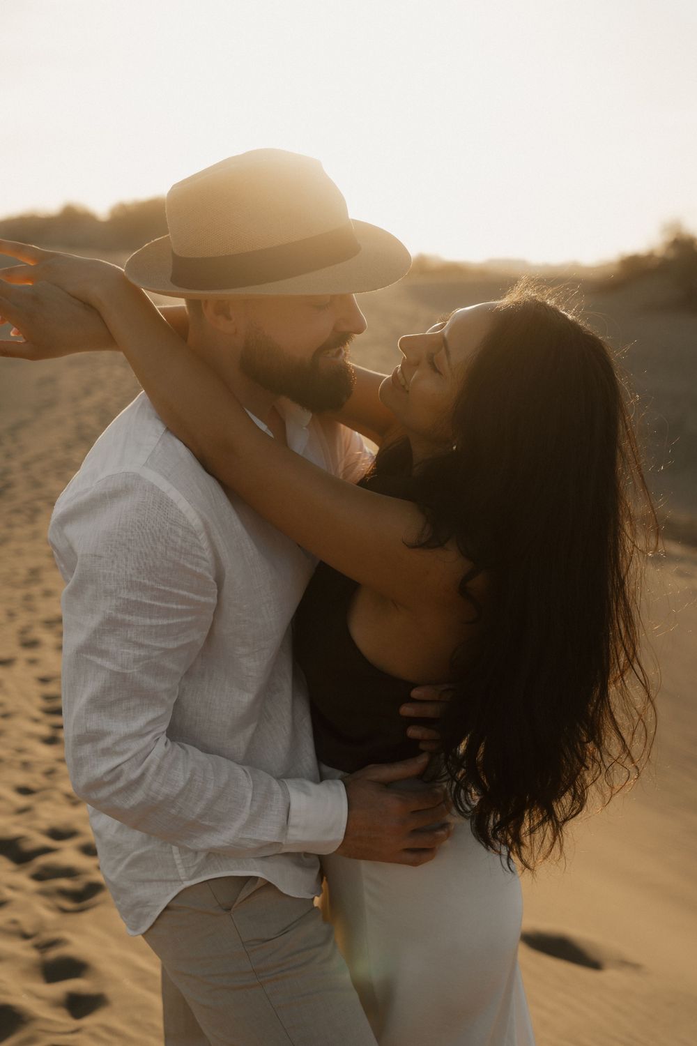 Cinematic sunset portrait of an engaged couple embracing in a vast desert landscape.