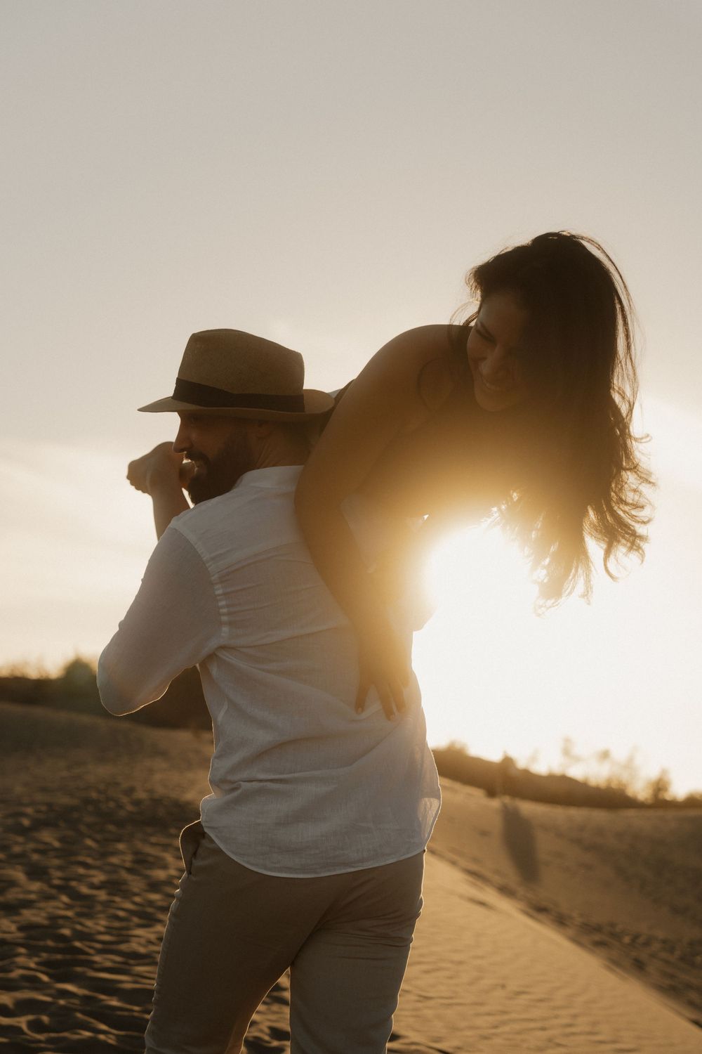Final poetic shot of an engaged couple walking away into the endless sand dunes.