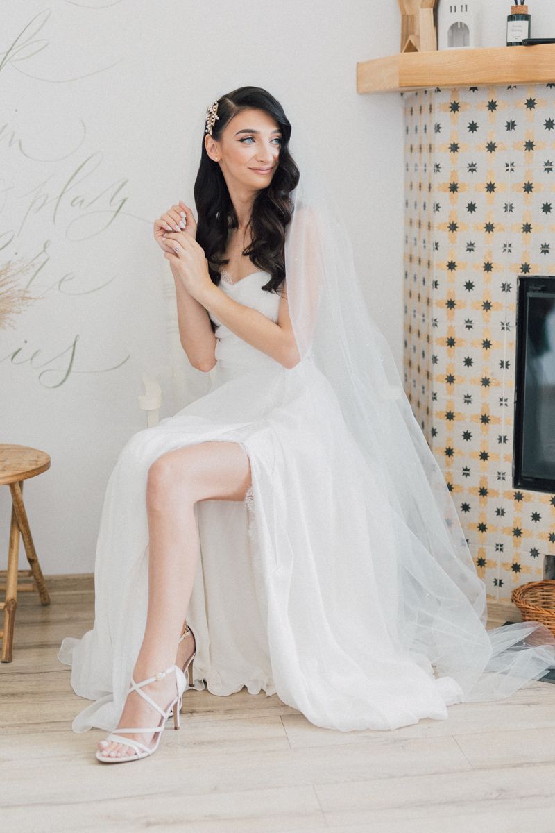 Elegant bridal portrait showing wedding dress details and shoes in a light-filled room.