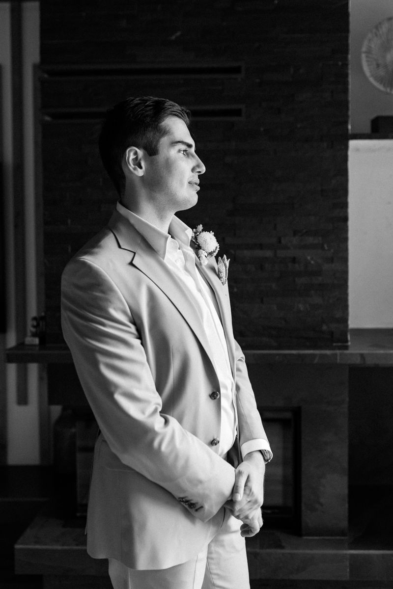 Dramatic black and white portrait of someone in a light colored suit jacket.