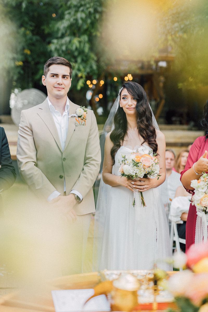 Wedding ceremony setup with beige and white color scheme in an outdoor garden setting.