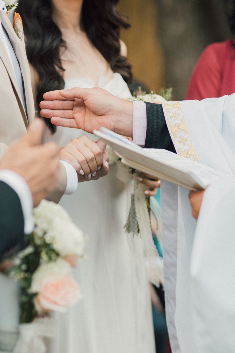 Close-up of hands exchanging wedding vows with white dress and formal attire.