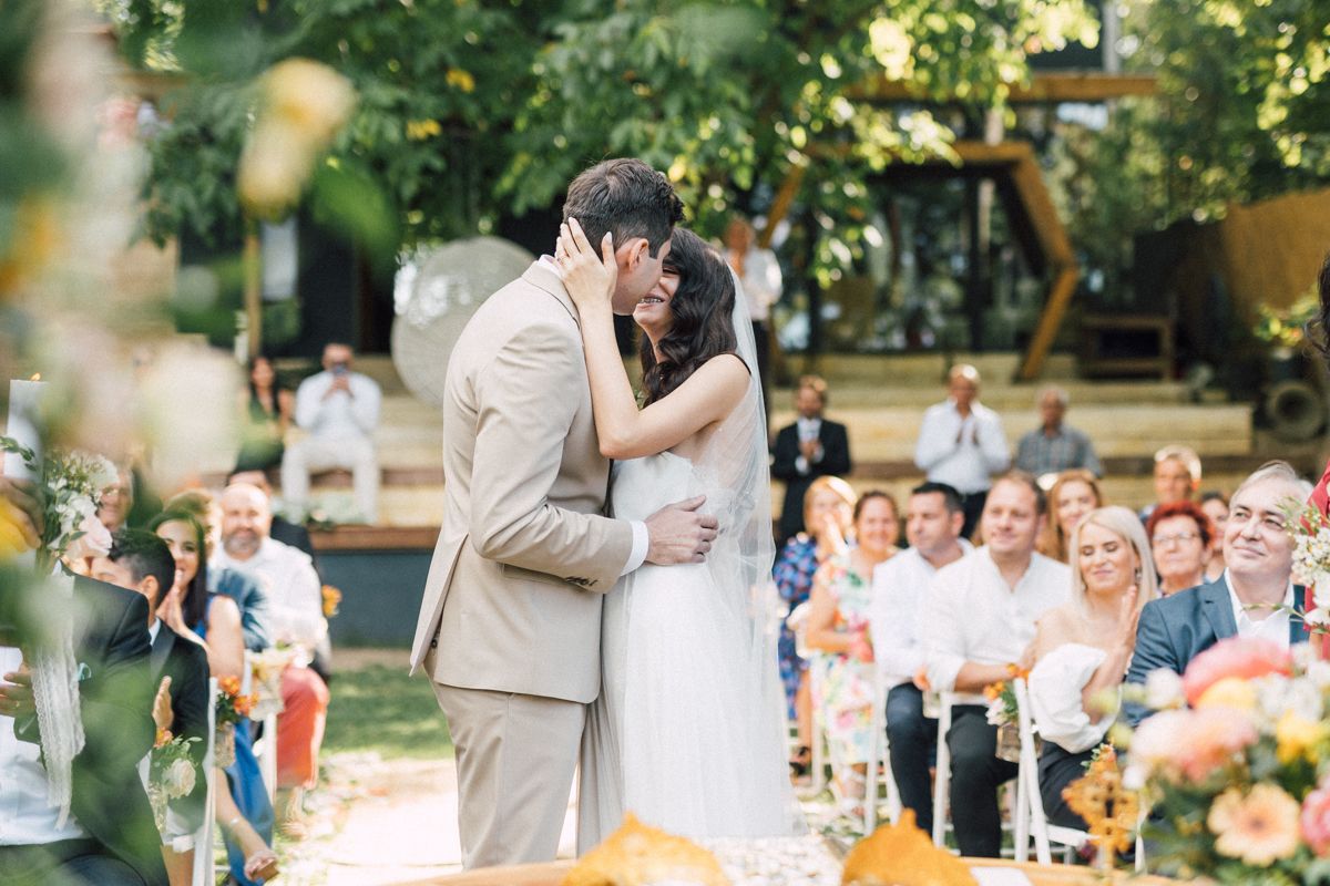 Garden wedding celebration with wooden arch and natural greenery backdrop.