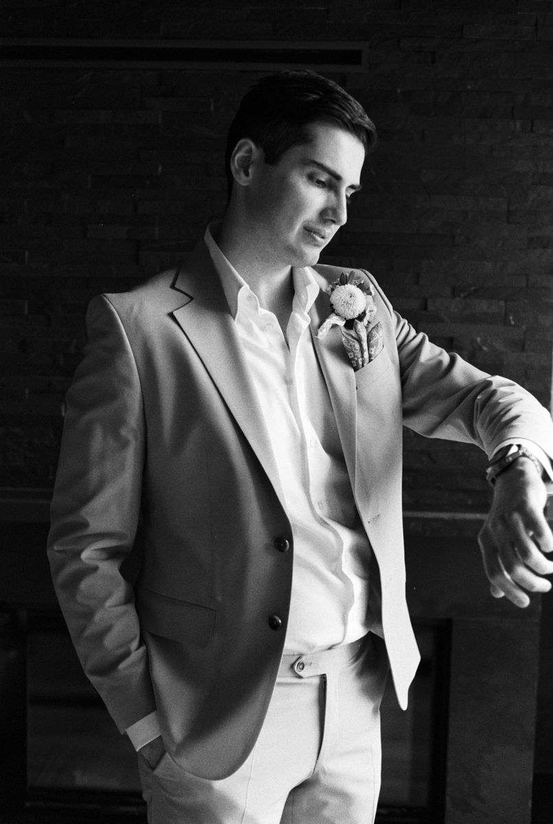 A formal suit detail shot showing light colored jacket and white shirt in dramatic lighting.