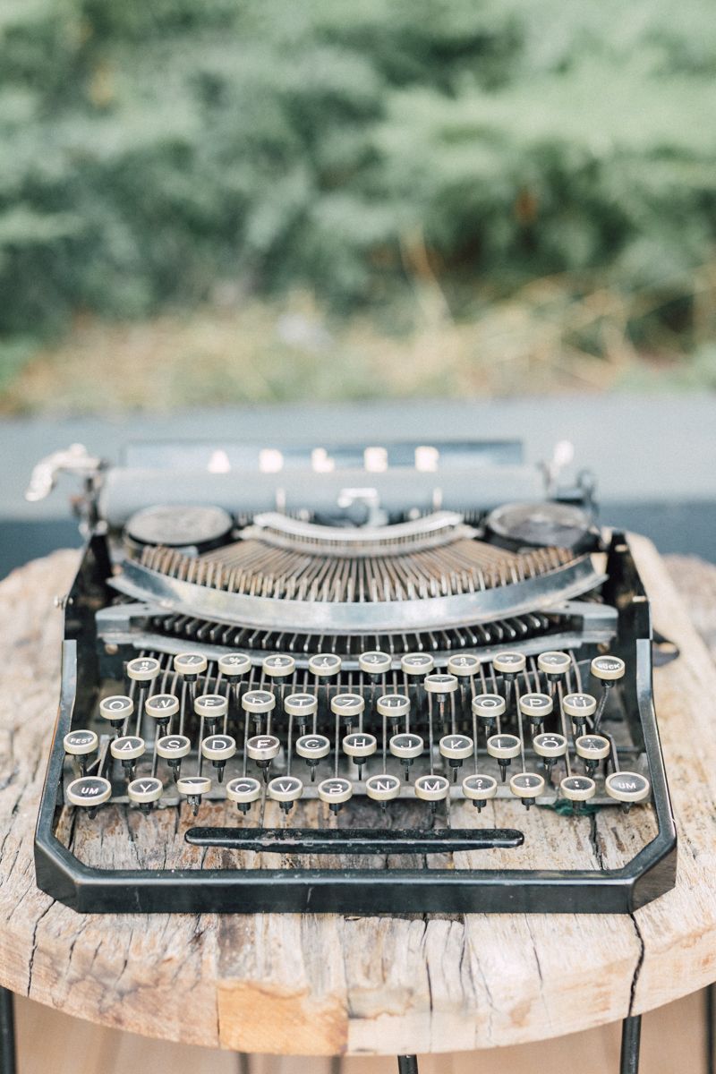 Vintage typewriter displayed on rustic wooden surface at wedding reception.
