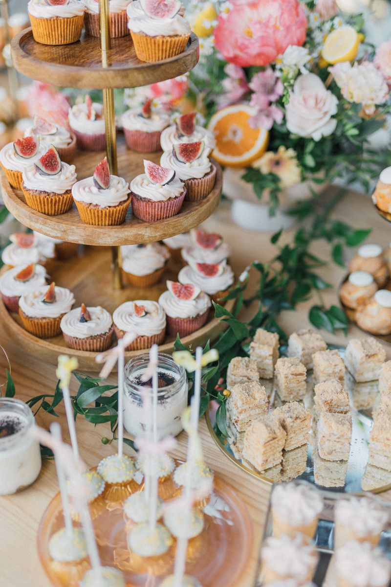 Tiered dessert display with cupcakes and treats decorated in pink and white.