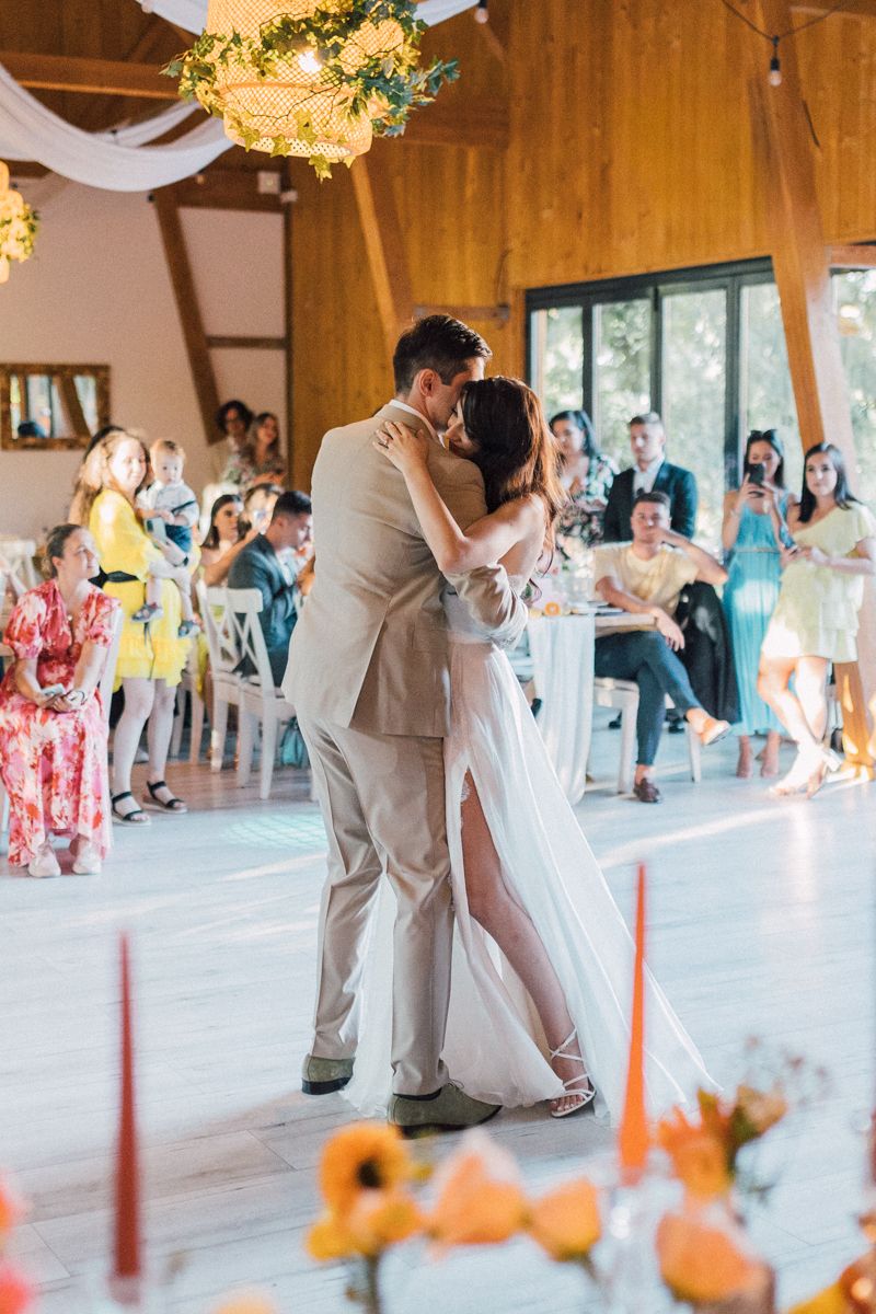 Couples dance together at a rustic barn wedding reception with warm lighting and floral decorations.
