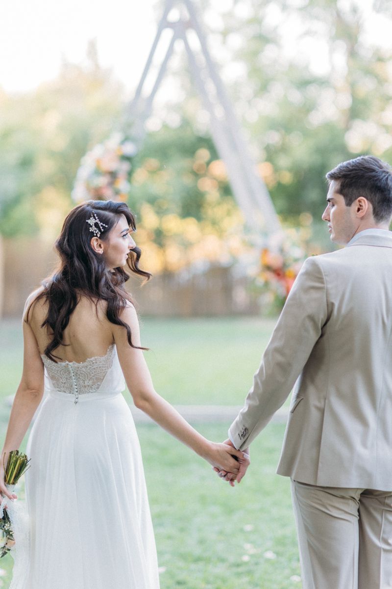 A romantic wedding photoshoot in a garden with a couple in beige and white attire.