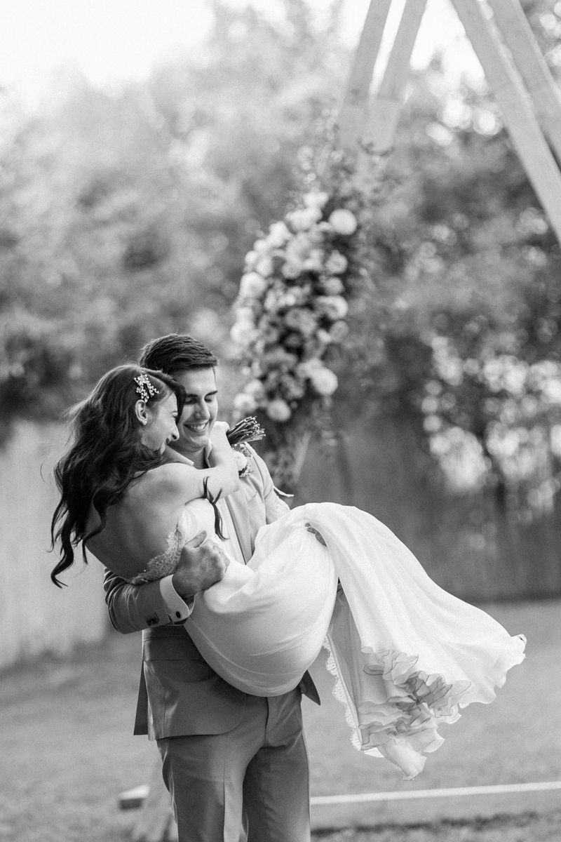 Black and white wedding photos showing playful dance moves in an outdoor setting.