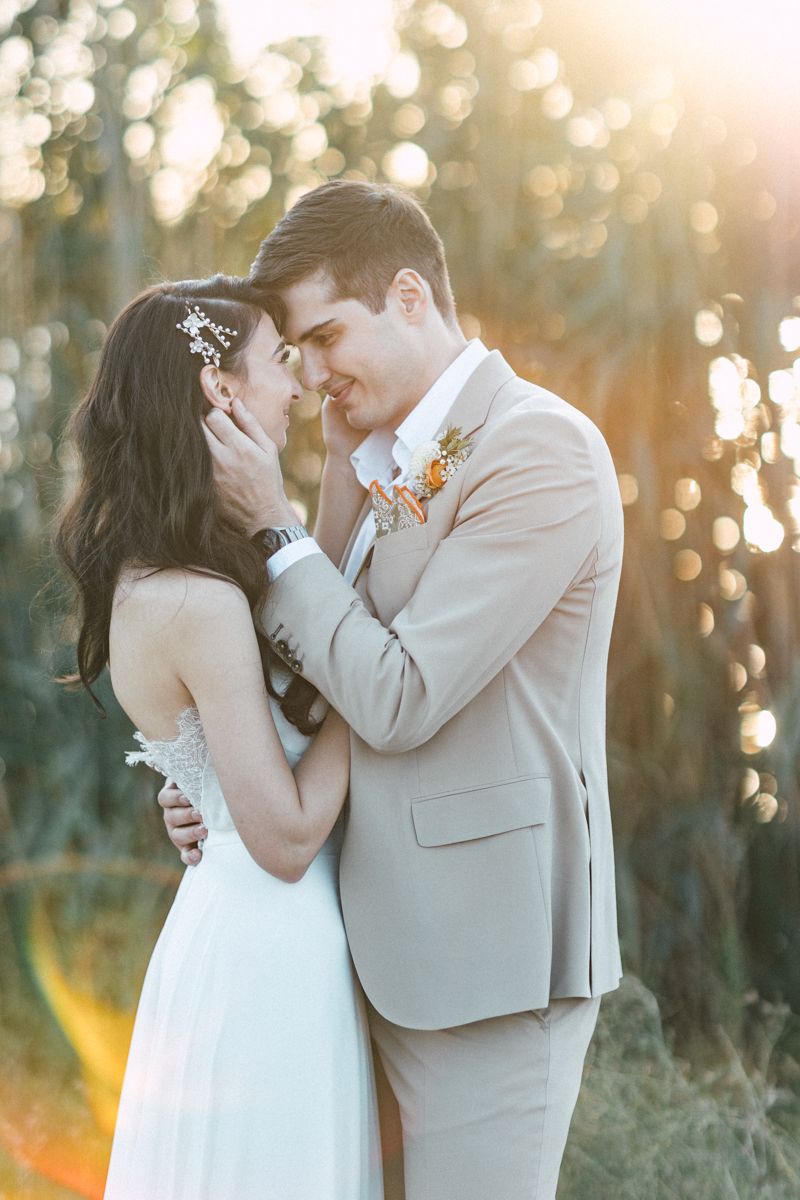 Wedding couple shares intimate moments in golden sunlight with bokeh background.