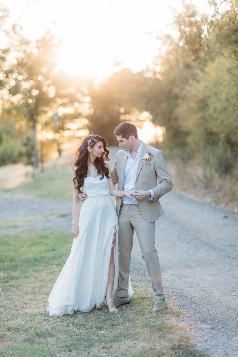 Wedding couple poses playfully on a dirt path during golden hour photography session.