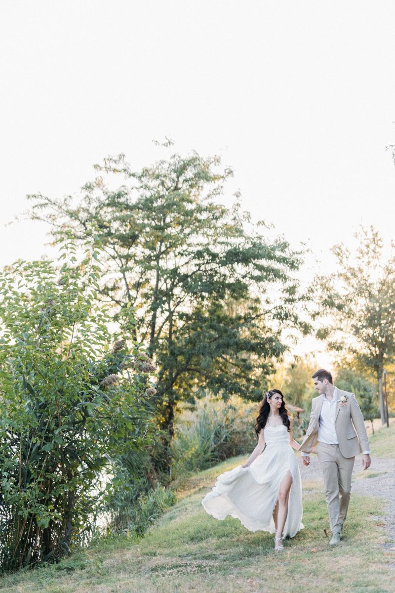 Ethereal wedding photos taken on a grassy hillside with trees during sunset.
