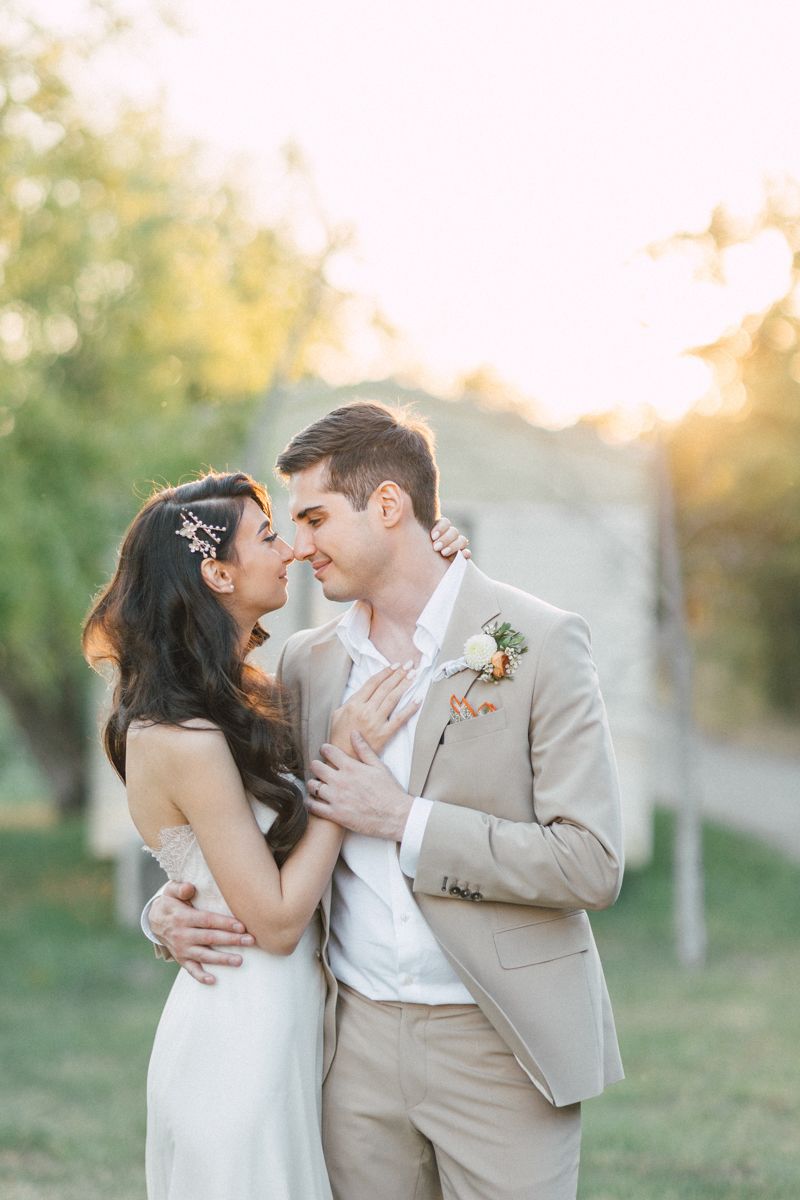 Romantic wedding couple sharing tender moments during golden hour sunset photo session.