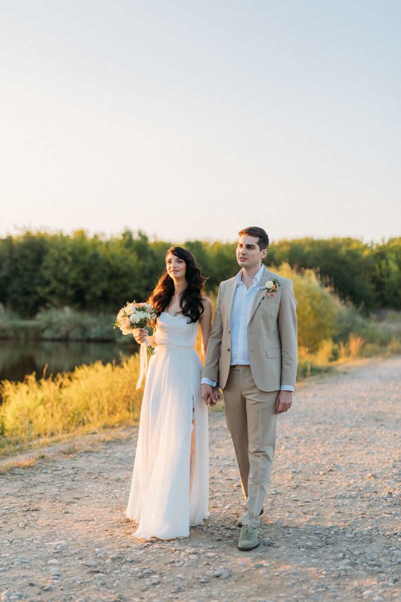 Couple walking hand in hand along a scenic desert path during their wedding photoshoot.