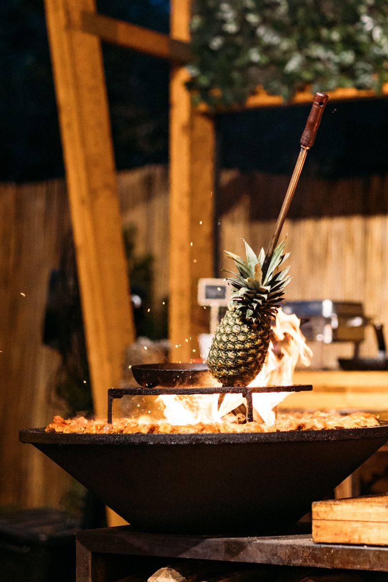 Rustic outdoor fire pit with pineapple decoration and ambient lighting at night.