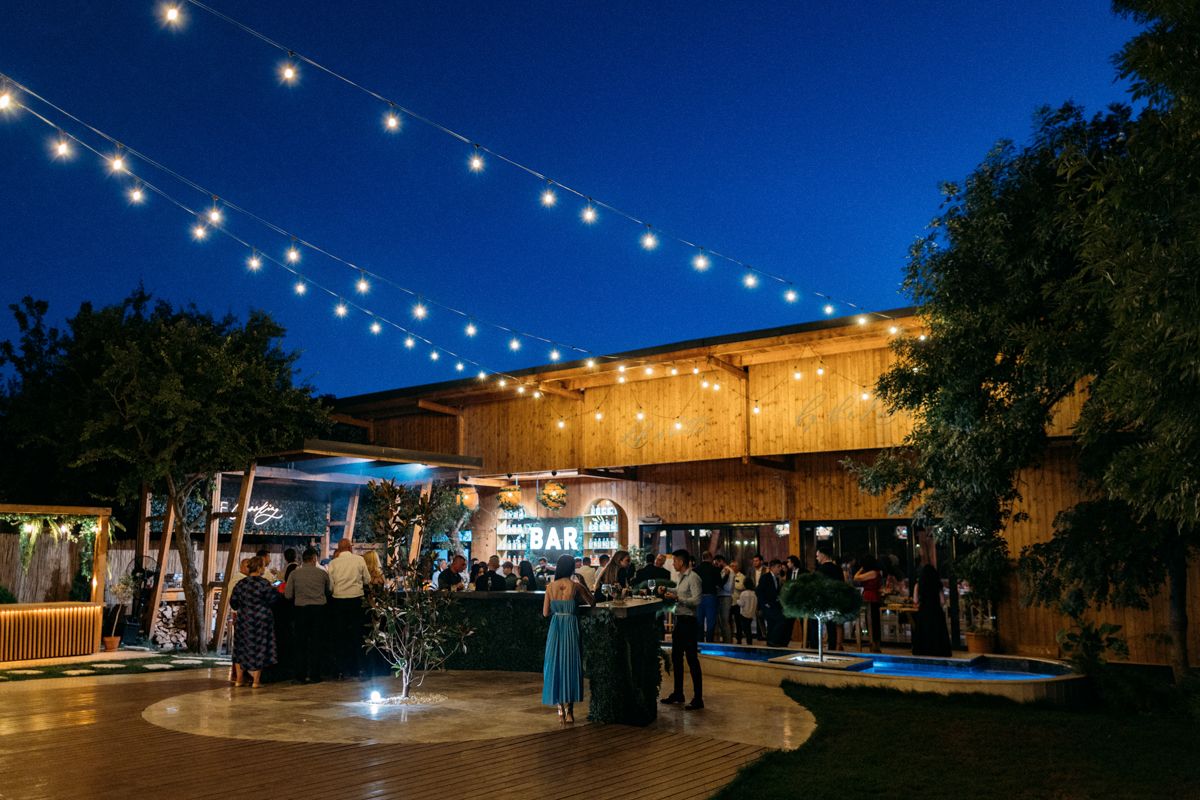Evening wedding reception venue with string lights creating magical ambiance under dark blue sky.