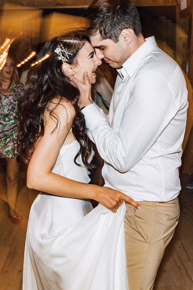 Wedding couple sharing intimate dance moments in rustic venue setting.