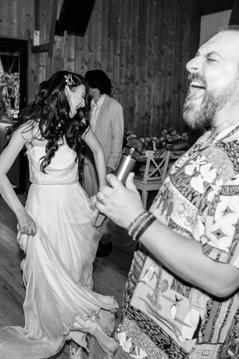 Wedding guests dancing and celebrating joyfully in a rustic barn setting.