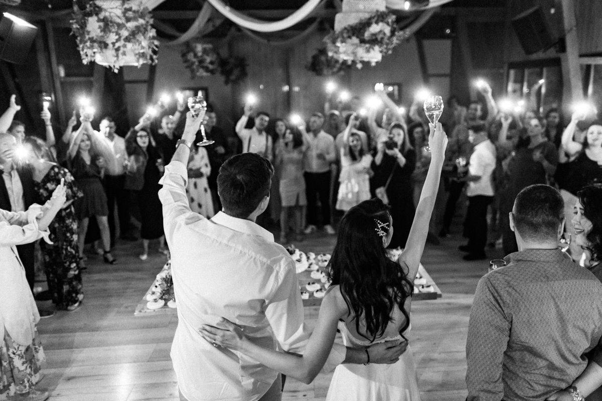 Wedding reception dance floor filled with guests celebrating under dim lighting.