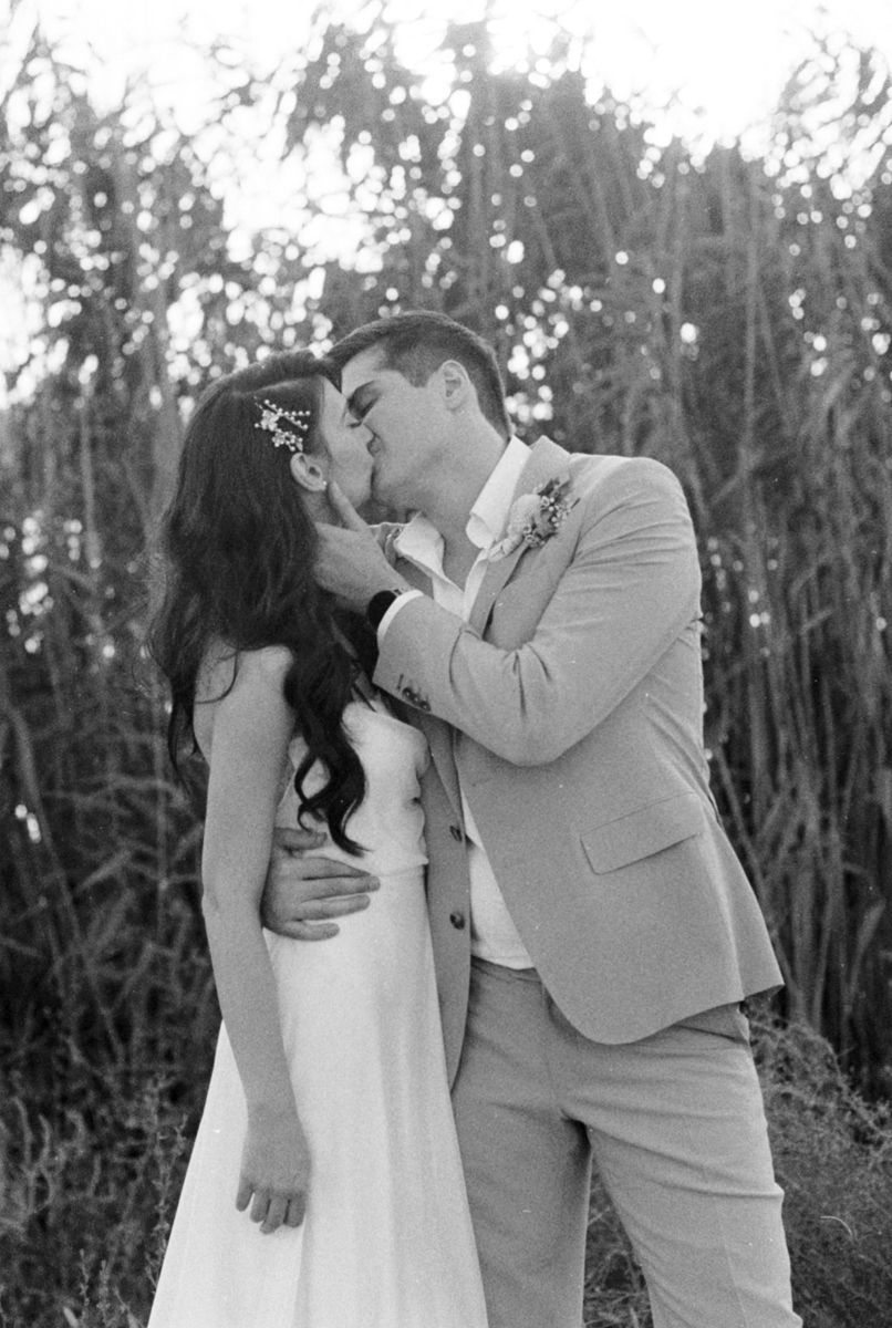 A romantic moment between newlyweds against a natural backdrop of trees and foliage.