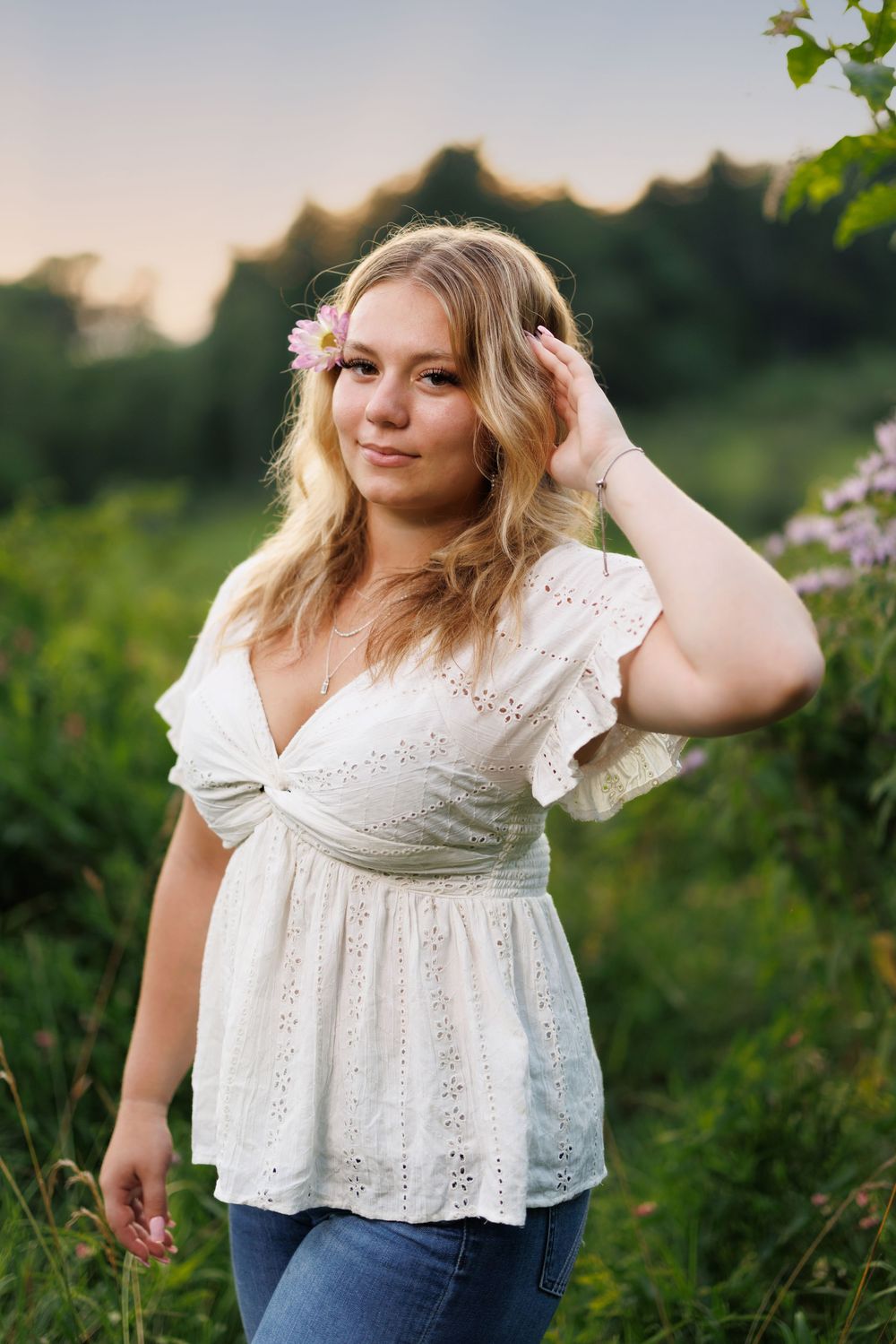 A white eyelet lace top styled against a natural green garden background.