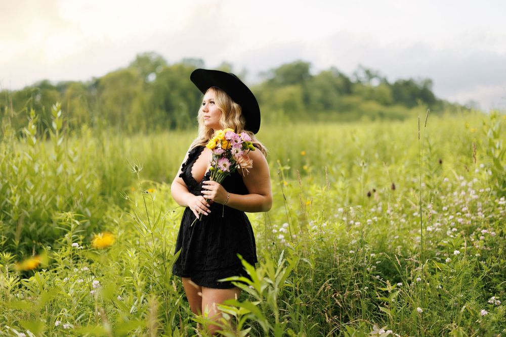 A wildflower meadow with tall grass and yellow flowers stretches across a sunny field.