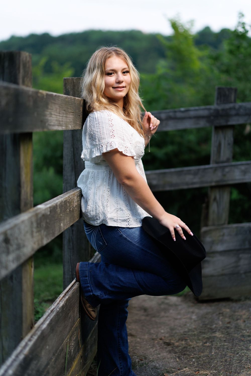 A rustic wooden fence provides a backdrop for an outdoor portrait session at sunset.